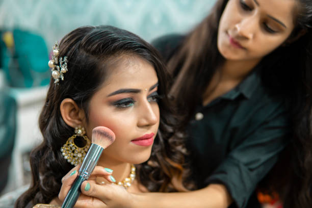 anu-9 Female makeup artist doing makeup of a beautiful Indian woman for a wedding reception at the beauty parlor.